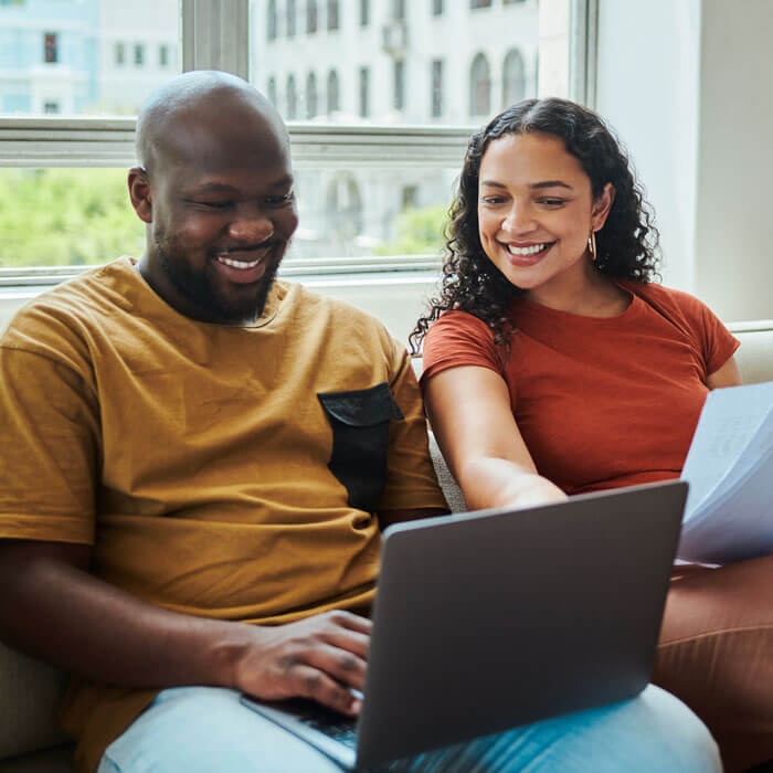 A young happy couple working on their budget and finances on a sofa