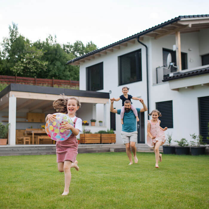 A father with three daughters playing outdoors in the backyard