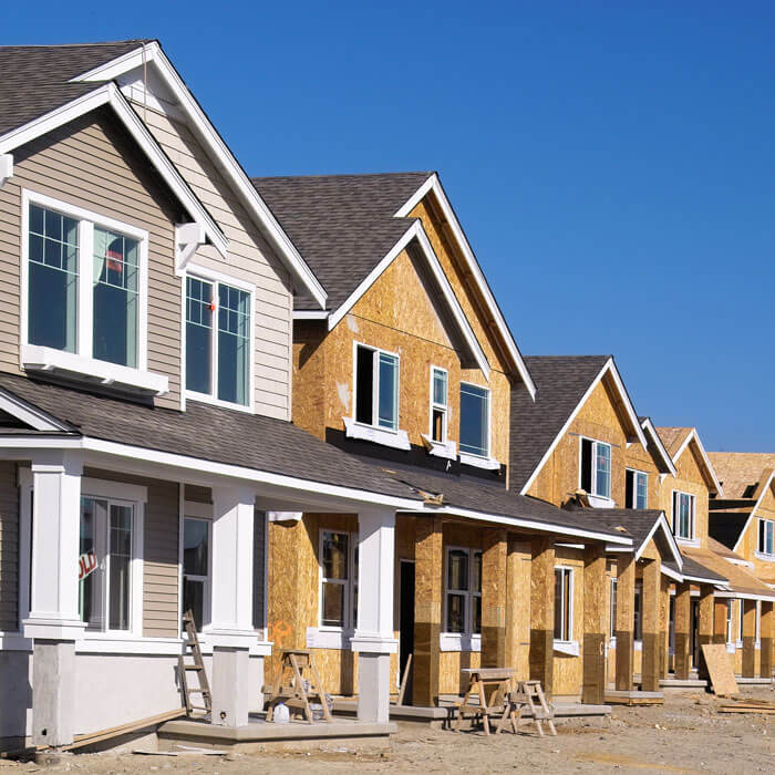 Perspective photo of a row of similar style houses during various phases of construction in a housing development