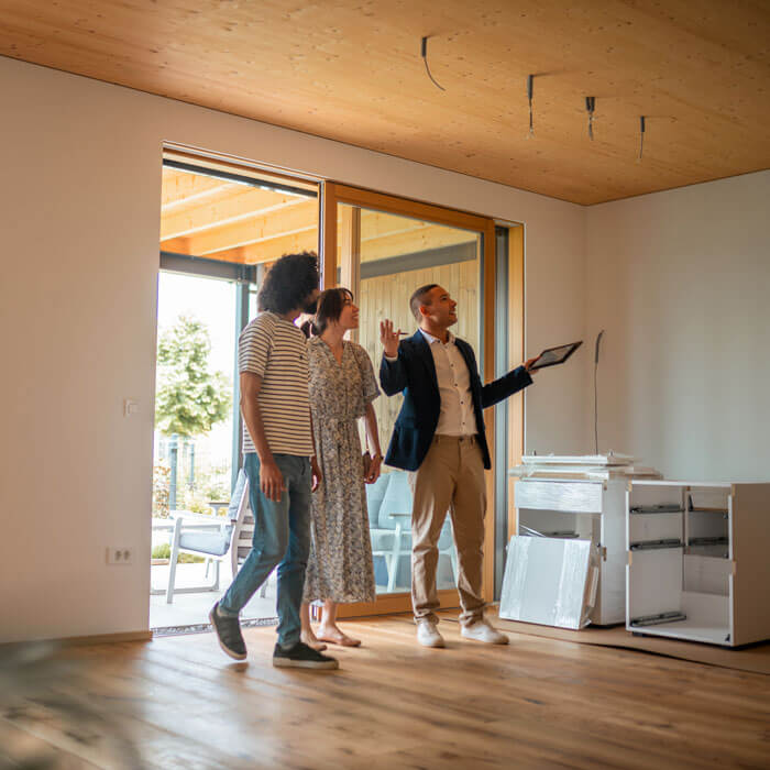 male real estate agent engages with a couple, presenting features of a spacious, sunlit home